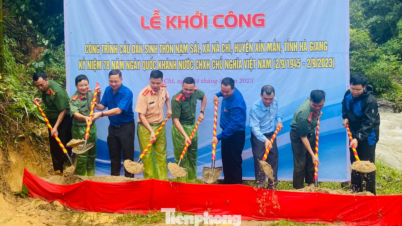 Trong ảnh, Đại úy Nguyễn Đức Minh, cán bộ Phòng Cảnh sát QLHC về TTXH CA tỉnh Hà Giang, anh Lộc Văn Huy (Bí thư Huyện Đoàn Xín Mần), anh Hạng Thanh Tùng (Phó Bí thư Huyện Đoàn Xín Mần), ông Hoàng Văn Dũng (Bí thư Đảng ủy xã Nà Chì), cùng các cán bộ và đoàn viên thanh niên đội mưa thực hiện lễ khởi công xây dựng cầu Nậm Sái.