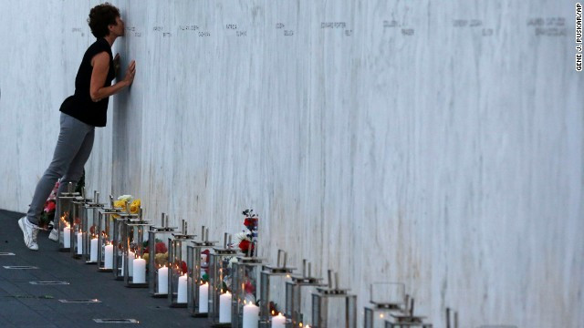 Cô gái hôn lên tên của người thân trong vụ khủng bố 11/9 sau khi đặt hoa và nến ở dưới 