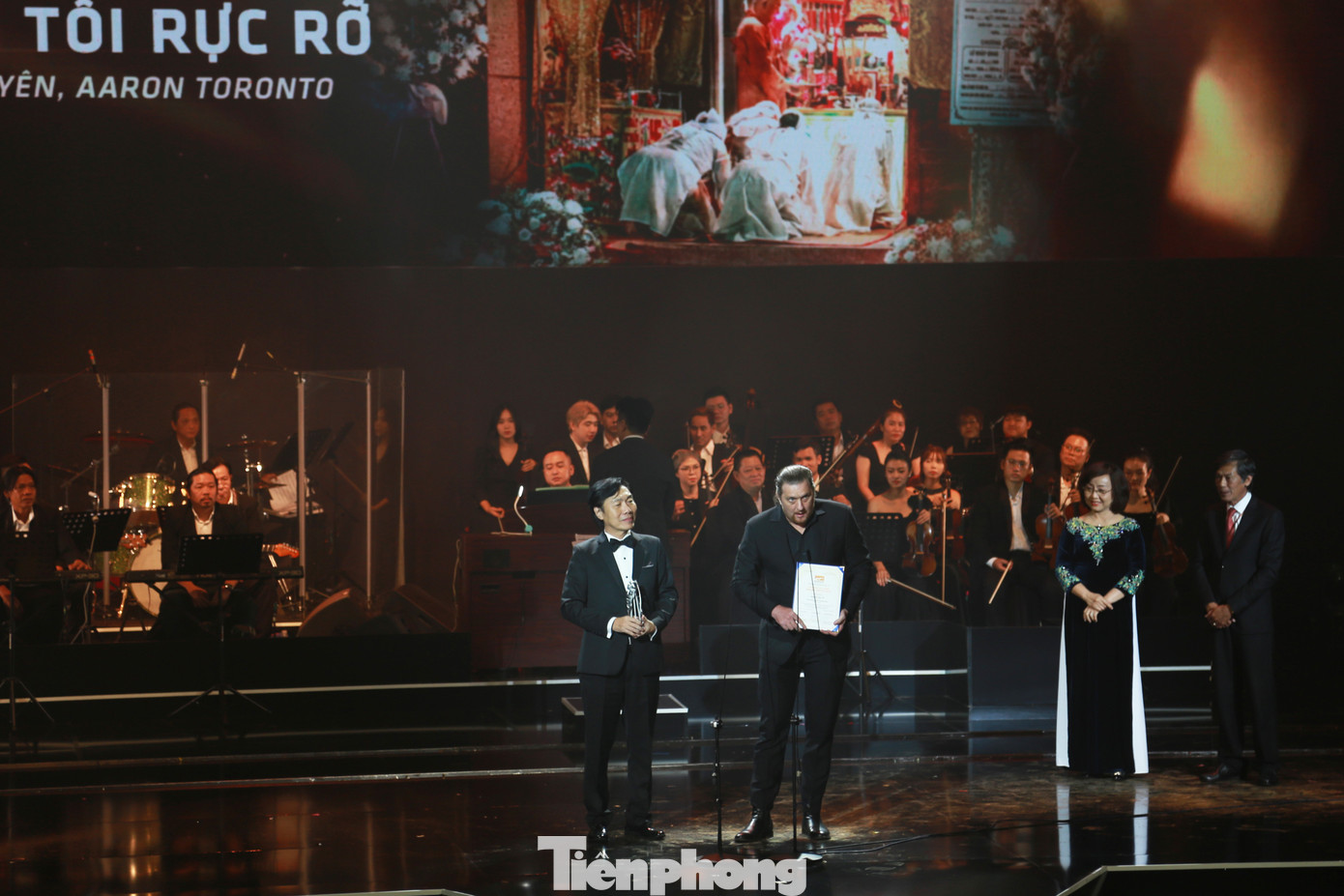 Đạo diễn Aaron Toronto và nam diễn viên Huỳnh Kiến An đại diện đoàn phim Đêm tối rực rỡ nhận Giải đặc biệt của Ban Giám khảo ở Hạng mục Phim Việt Nam
