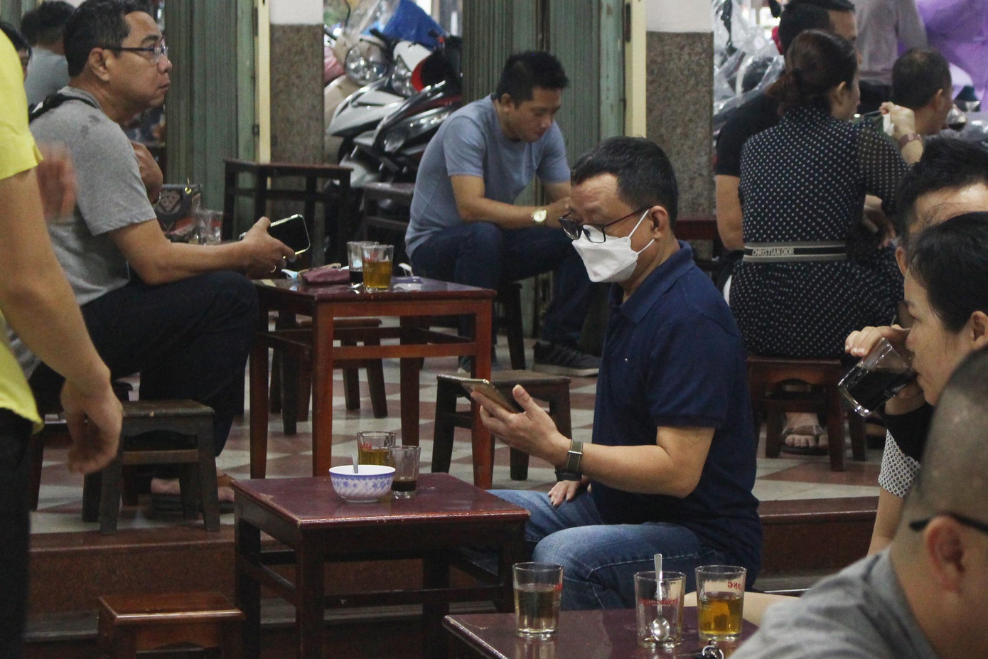 Nhiều người còn cẩn thận đeo kín khẩu trang, chỉ mở ra lúc uống cafe.