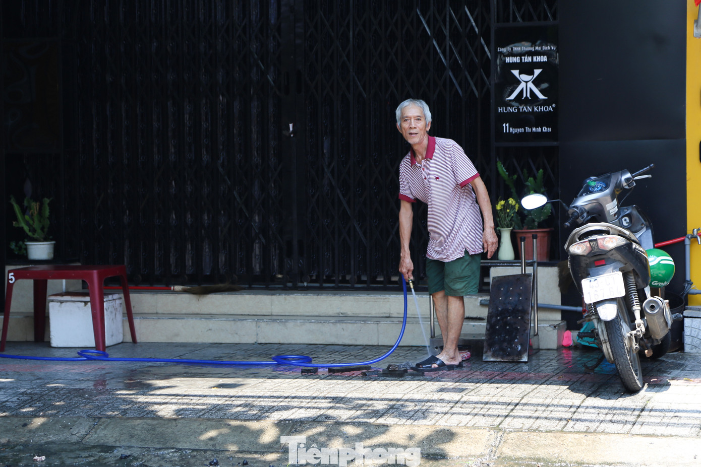 Một người dân trên đường Nguyễn Thị Minh Khai (quận Hải Châu) dùng vòi xịt xối nước ở khu vực vỉa hè trước nhà để giải nhiệt.