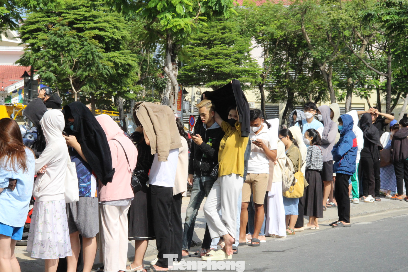 Các khán giả trẻ cũng sẵn sàng áo khoác, mũ, ô... để che nắng và chờ đợi trong thời gian dài để cầm trên tay tấm vé của bộ phim Đào, phở và piano. Ảnh: Giang Thanh.