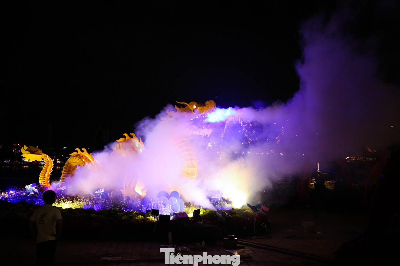 Linh vật rồng huyền ảo, lấp ló sau làn khói nhiều màu sắc, phía sau chính là Cầu Rồng - cây cầu biểu tượng của Đà Nẵng. Nhiều người dân và du khách sẵn sàng chờ đợi cả tiếng đồng hồ để ghi lại những khoảnh khắc độc đáo này.