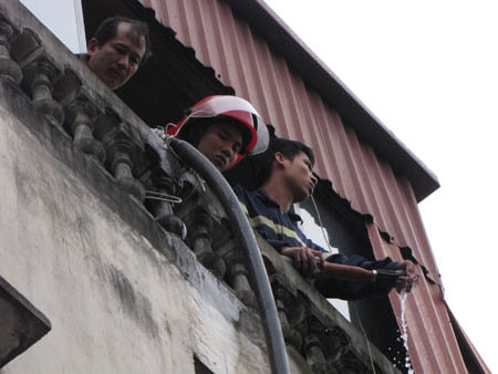 Một bộ phận phải mang vòi nước sang nhà bên cạnh, chữa cháy trên nóc ngôi nhà số 155 Nguyễn Thái Học