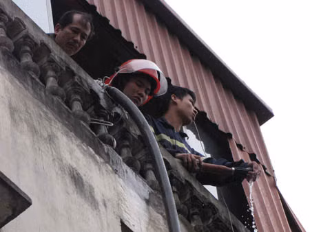 Một bộ phận phải mang vòi nước sang nhà bên cạnh, chữa cháy trên nóc ngôi nhà số 155 Nguyễn Thái Học