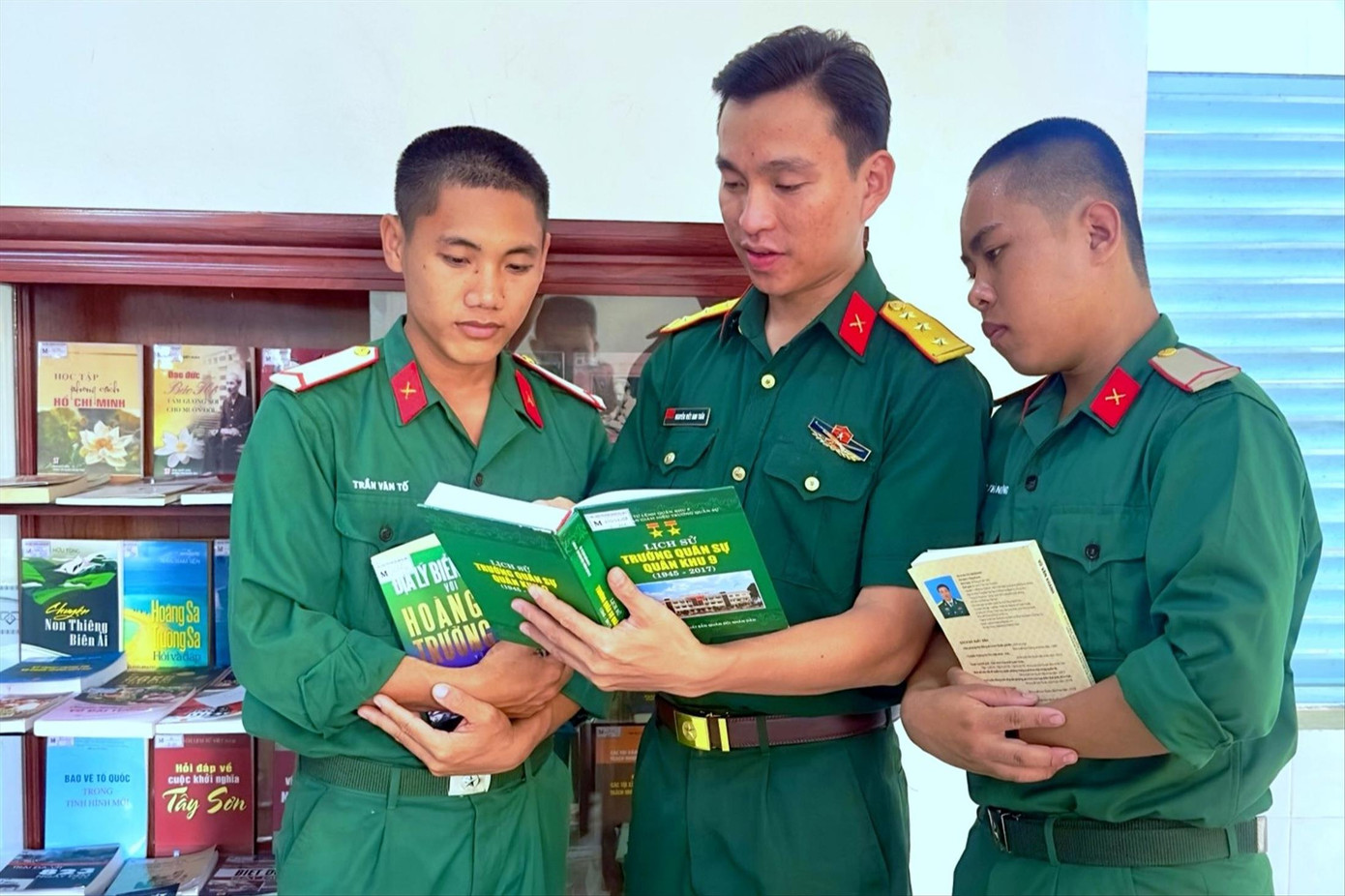 Thượng úy Nguyễn Viết Anh Tuấn (đứng giữa) bên “Tủ sách quân nhân” ở đơn vị