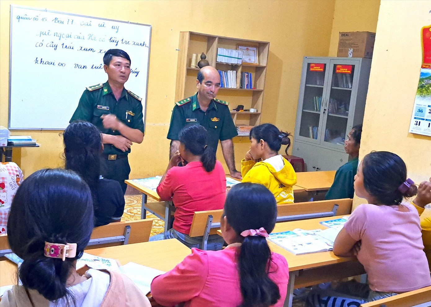 Trung tá Nguyễn Văn Thành (bên trái) giải thích cho bà con giá trị của biết chữ