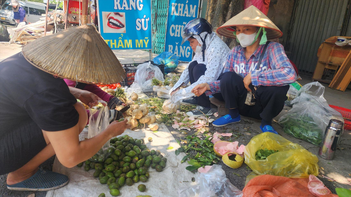 Hằng ngày, chị Nguyễn Thị Vân (đội nón, bìa phải) buôn bán rau củ để kiếm thêm thu nhập.