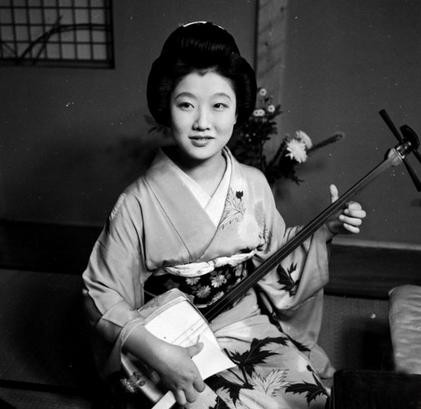 Năm 1950, một Geisha xinh đẹp đang gẩy đàn tam phục vụ khách