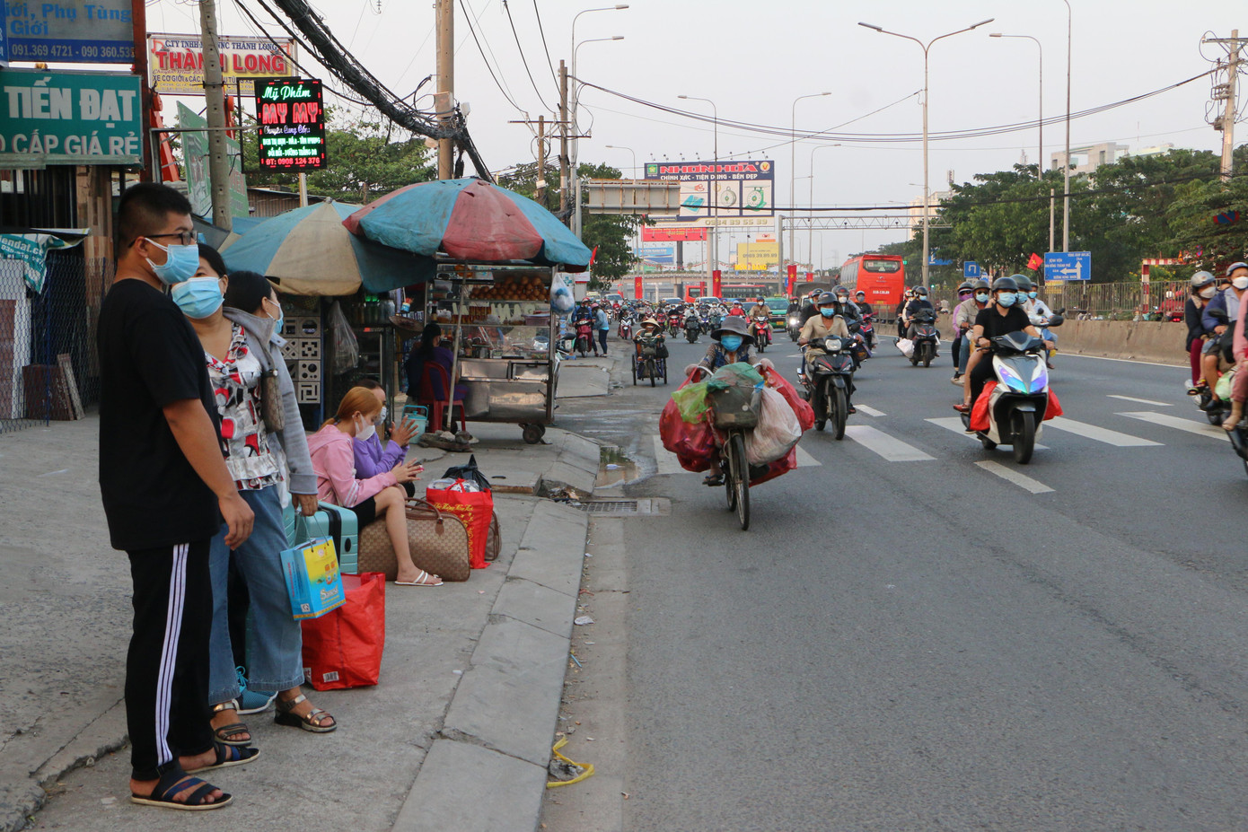 Chia sẻ với Tiền Phong, bà Nguyễn Thị Mai (quê An Giang) cho biết: “Từ khi dịch bùng phát ở TPHCM đến nay gia đình chúng tôi chưa về thăm ông, bà ở quê. Dịp Tết này, tôi đặt vé xe để cả nhà cùng về”. Trong ảnh: Một gia đình đợi xe về quê trên Quốc lộ 1 (huyện Bình Chánh, TPHCM).