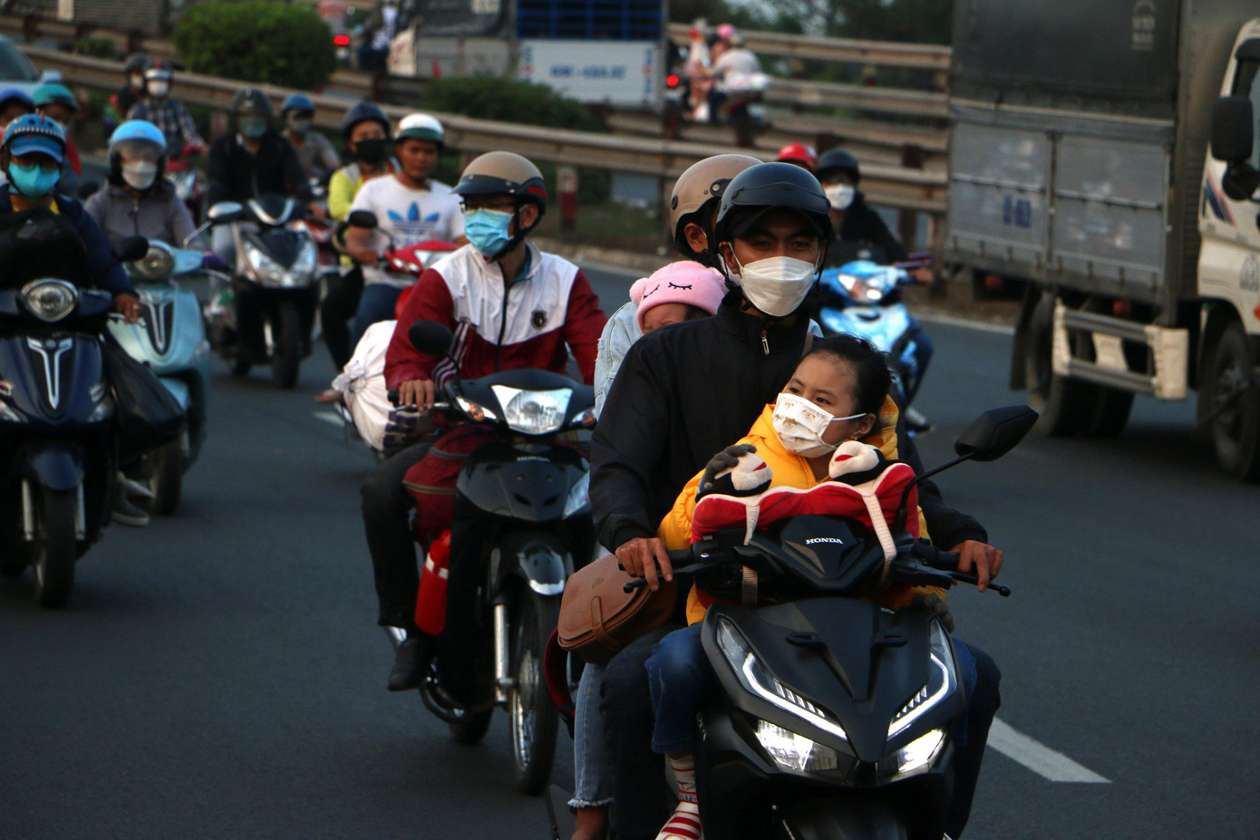 Trẻ nhỏ trên xe máy theo bố mẹ về quê ăn Tết.