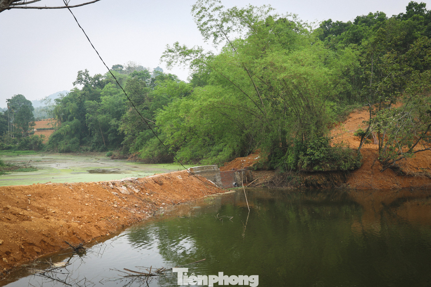 Ghi nhận của PV Tiền Phong ngày 24/4 cho thấy, xung quanh hồ có nhiều diện tích bị đổ đất đá, trạc thải xây dựng lấn xuống lòng hồ, ngăn cản dòng nước từ thượng nguồn đổ về.