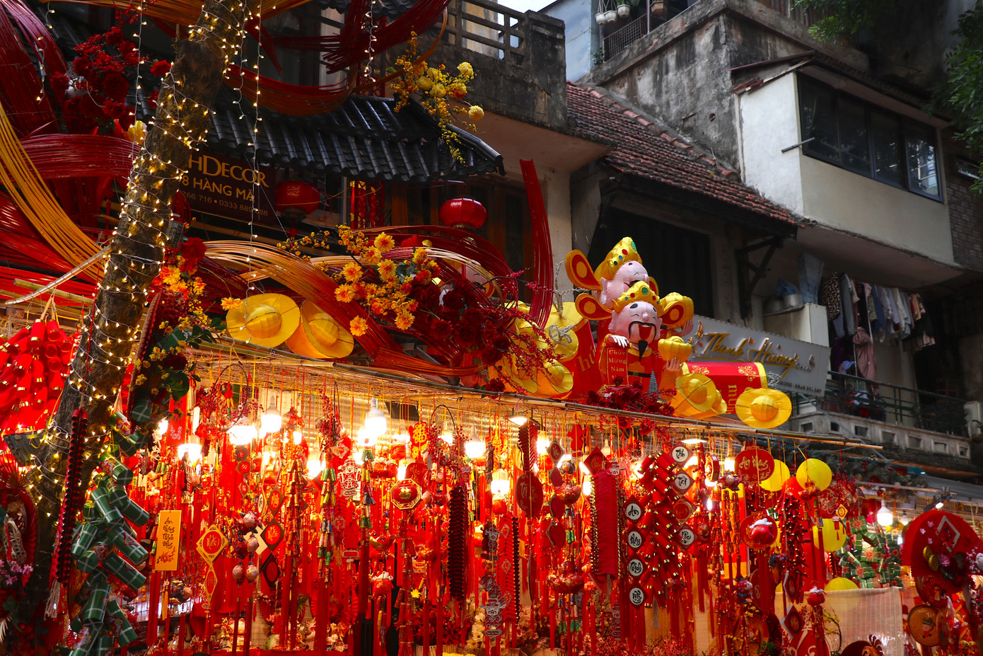 Cả con phố được phủ kín bởi màu sắc rực rỡ của đèn lồng, câu đối, dây may mắn, kim tuyến trang trí và những đồ vàng mã phục vụ cho ngày Tết. Những vật tượng trưng cho sự may mắn, an lành, hạnh phúc trong năm mới đến được bày bán nhiều với mẫu mã được cập nhật theo xu hướng năm nay.