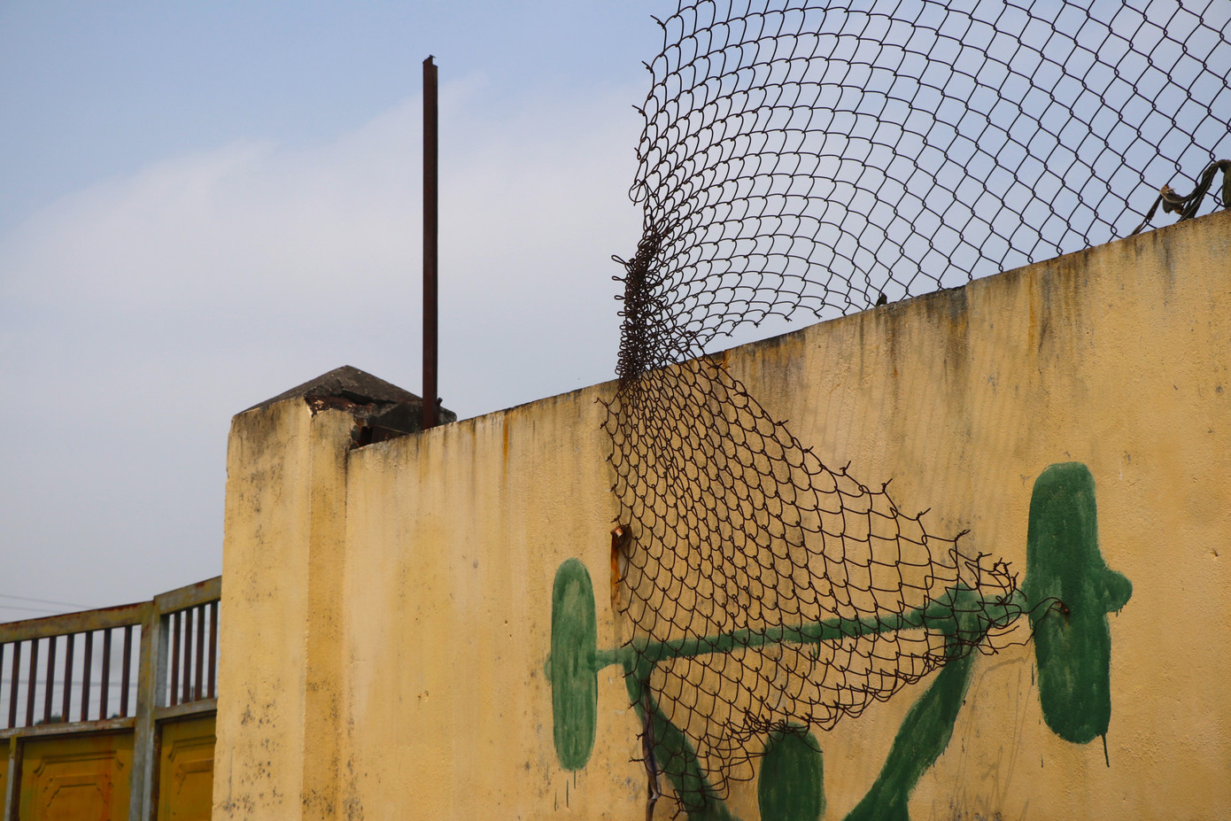 Những cánh cửa ra vào sân và hàng rào sắt hỏng hóc, rỉ sét, nhuốm màu thời gian.