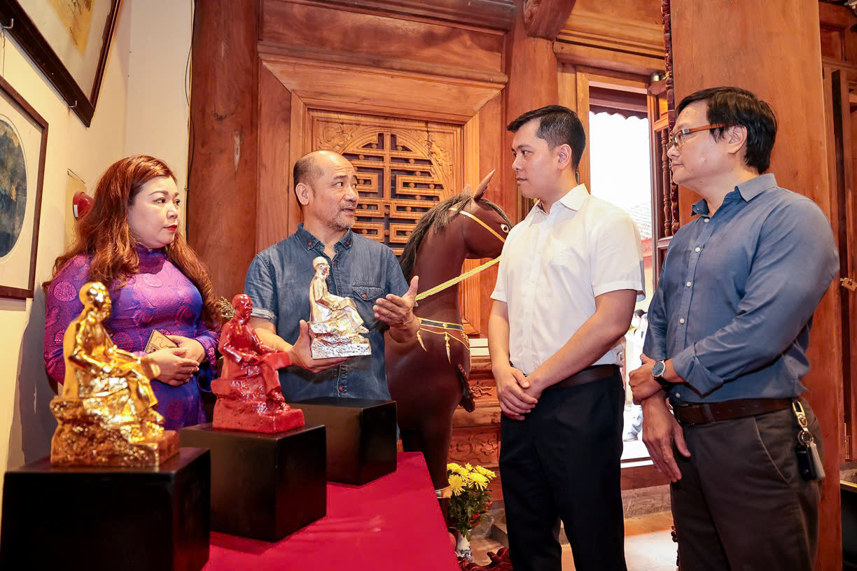 Hoạ sĩ Vũ Xuân Đông giới thiệu về tác phẩm “Bác Hồ ngồi đọc báo Nhân Dân” với các đại biểu.