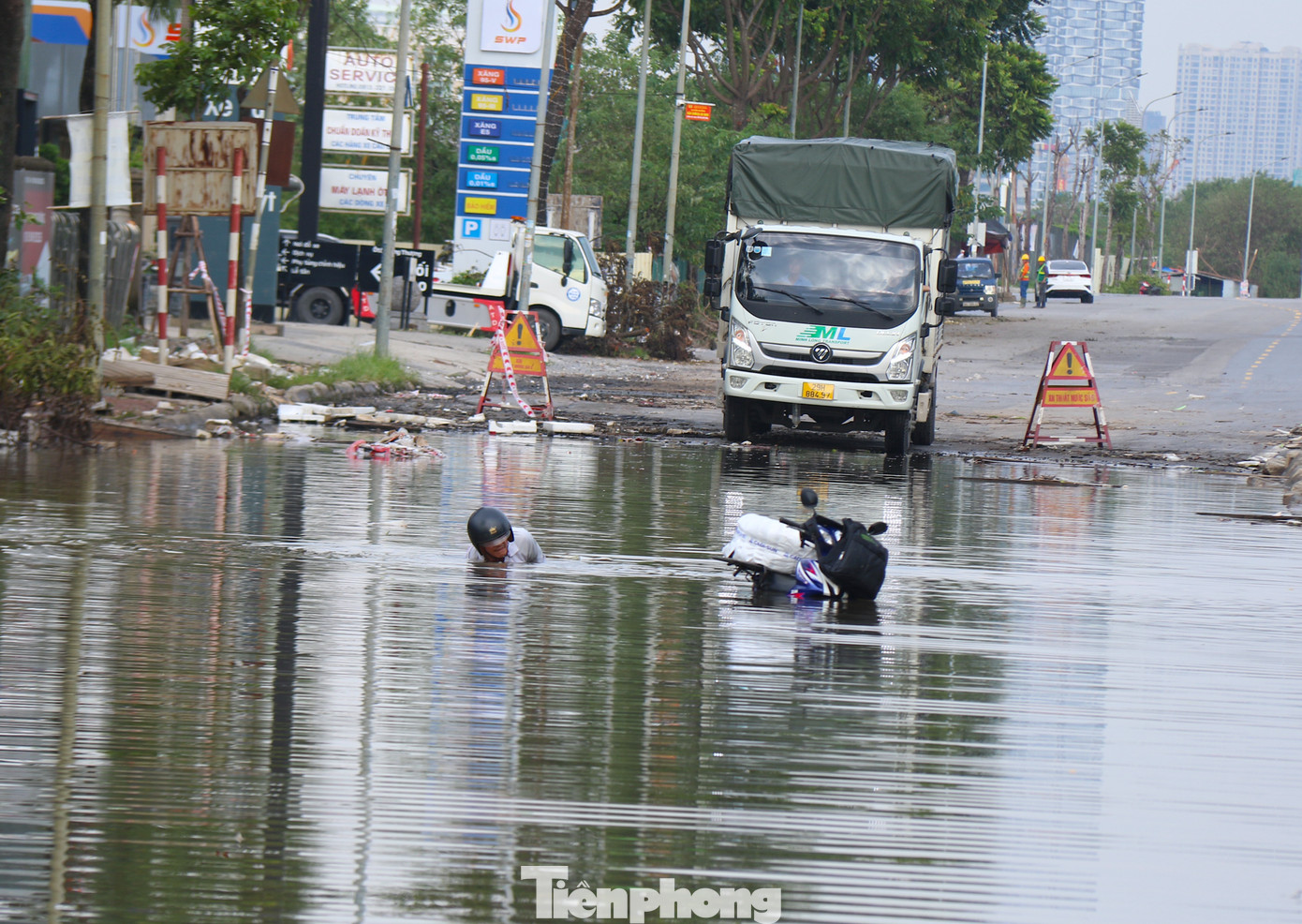 Người dân bì bõm lội nước vớt đồ do ngã xe khu vực ngập sâu trên đại lộ.
