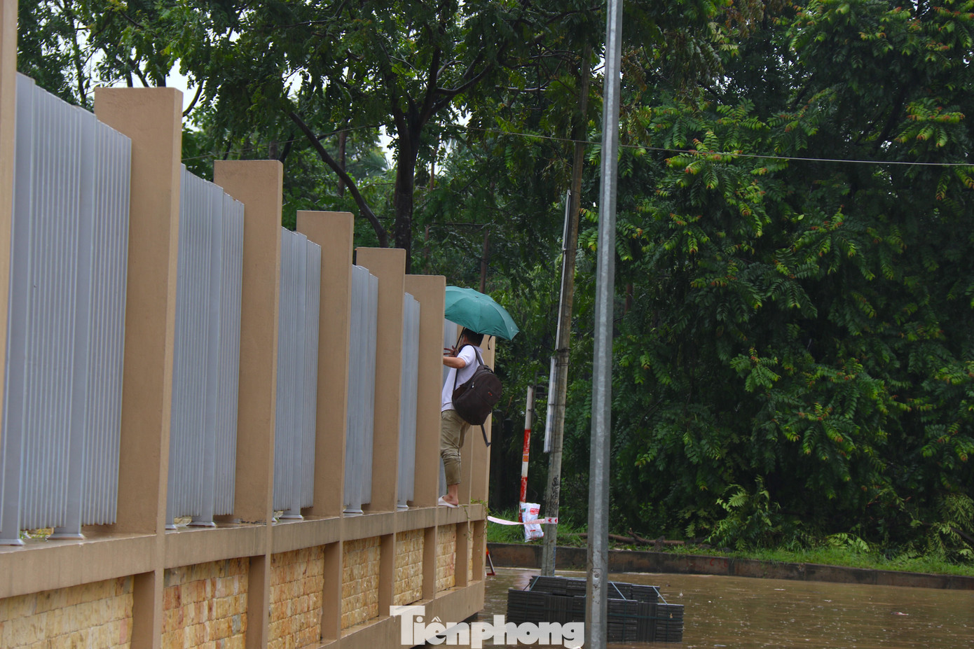 Để đi qua khu vực ngập, có người còn chọn trèo lên hàng rào. Để đi qua khu vực ngập, có người còn chọn trèo lên hàng rào.
