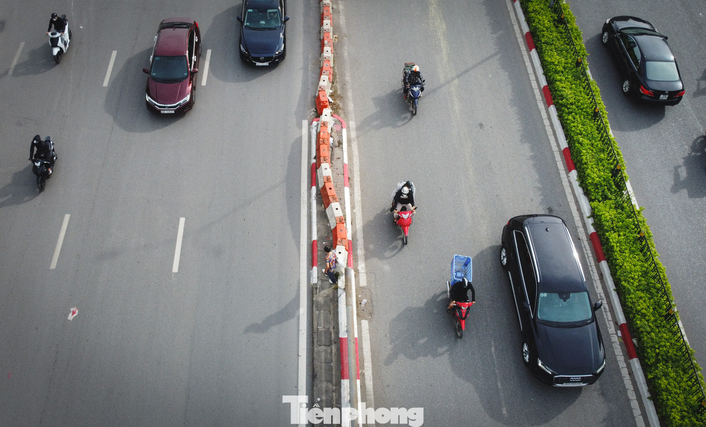 Người đi bộ leo qua dải phân cách để sang đường tiềm ẩn nhiều nguy cơ mất an toàn giao thông.