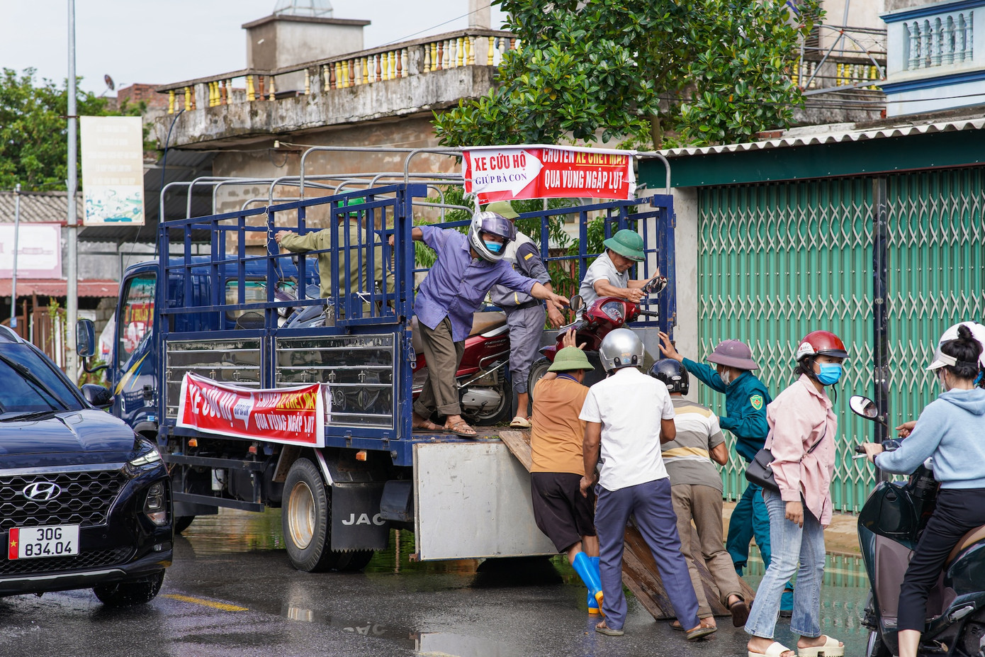 Xe tải hỗ trợ phương tiện và hoa màu đi qua khu vực ngập sâu.