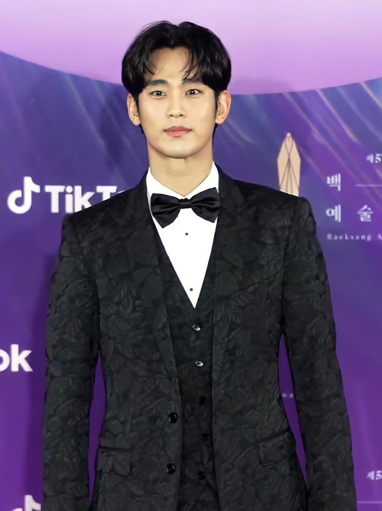 Kim Soo Hyun chọn trang phục đen nhưng có hoa văn nổi bật để tránh gây nhàm chán, nam tài tử gây bất ngờ với mái tóc dài và phần mái rẽ hình trái tim.