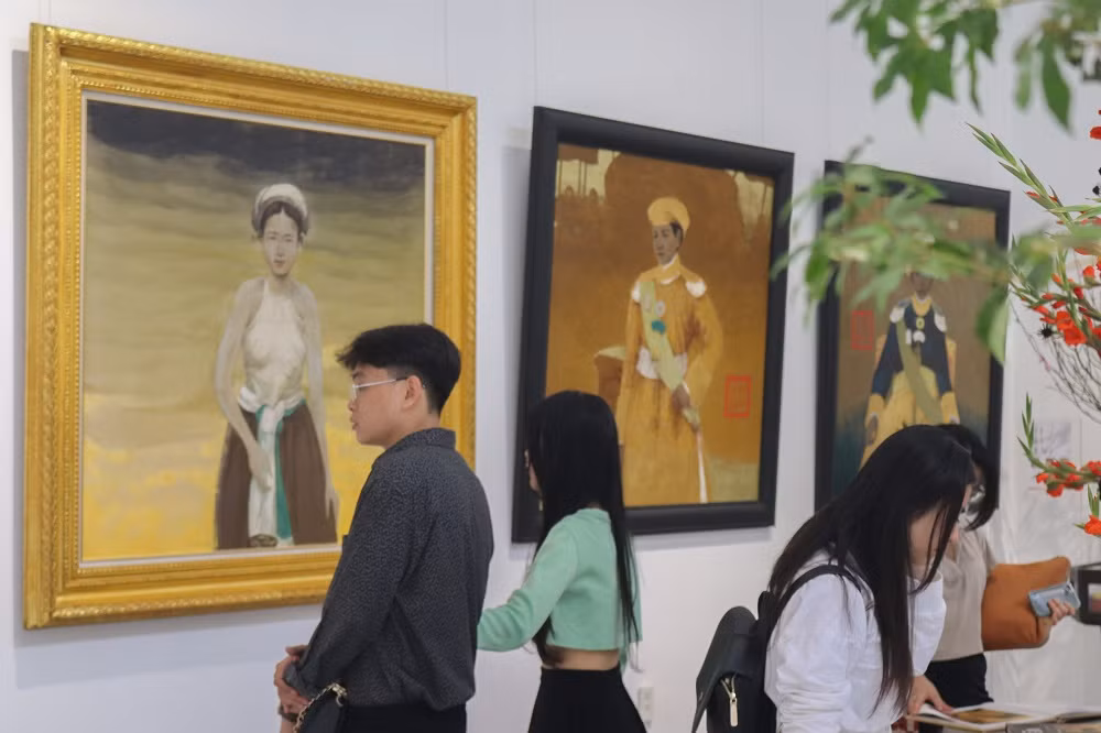 Các bạn trẻ xem tranh của hoạ sĩ Bùi Hữu Hùng tại triển lãm. (Ảnh: Trúc Nhi)
