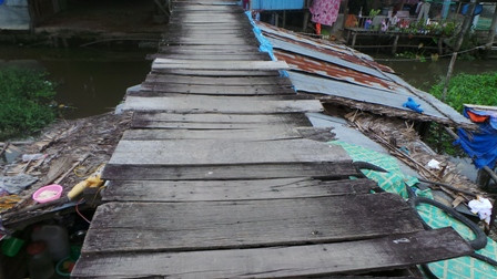 Mặt cầu bằng ván gỗ tạp, nhiều chỗ đã bị mục, tuột đinh, chông chênh như thế này
