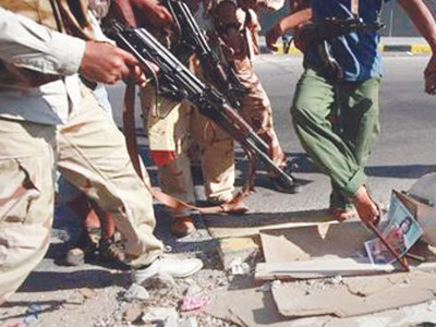 Quân nổi dậy chĩa súng vào ảnh ông Gadhafi Ảnh: Reuters