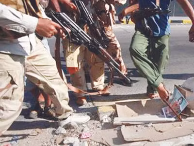 Quân nổi dậy chĩa súng vào ảnh ông Gadhafi Ảnh: Reuters