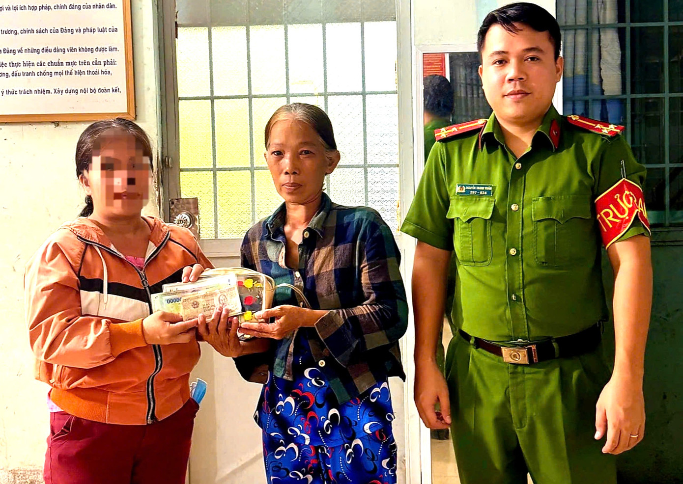 Bà Trương Thanh Trúc (giữa) bàn giao tài sản nhặt được cho người đánh rơi trước sự chứng kiến của công an địa phương