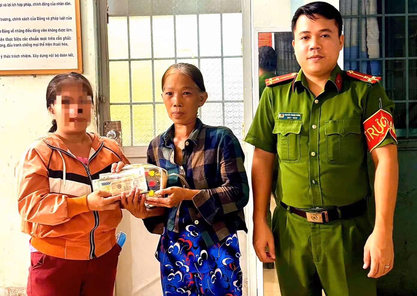 Bà Trương Thanh Trúc (giữa) bàn giao tài sản nhặt được cho người đánh rơi trước sự chứng kiến của công an địa phương