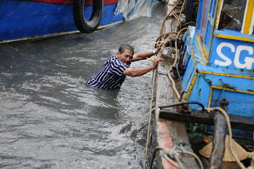 Một người đàn ông đang tìm cách neo thuyền khi sóng gió bắt đầu lớn đầu giờ chiều 1-4 - Ảnh: Thuận Thắng/Tuổi Trẻ