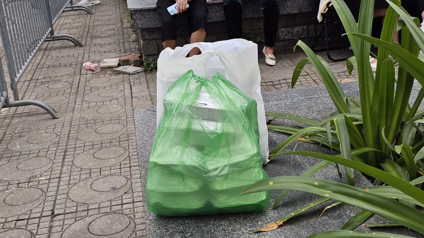 Người thân ở vòng ngoài chờ “tiếp tế” cơm hộp, bánh mì, nước uống.... cho những người tham gia đấu giá đất xuyên trưa.