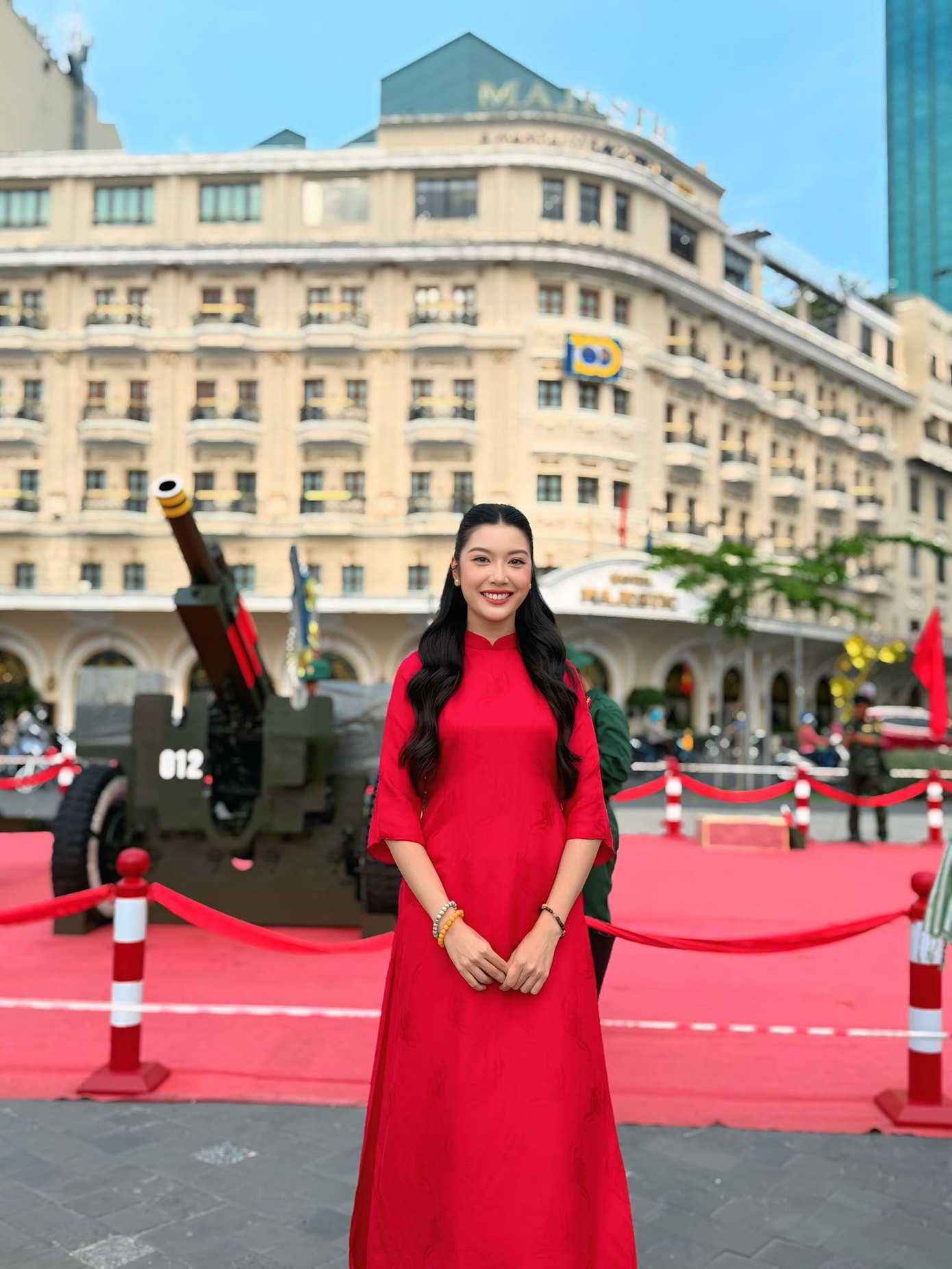 Á hậu Thúy Vân chụp ảnh với áo dài đỏ ở công viên bến Bạch Đằng - nơi đặt 18 khẩu pháo phục vụ lễ kỷ niệm 50 năm thống nhất đất nước.