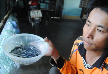 Mỗi ngày vợ chồng anh Sỹ và đứa con trai dùng miệng ngậm dăm không chì để gắn vào lưới 