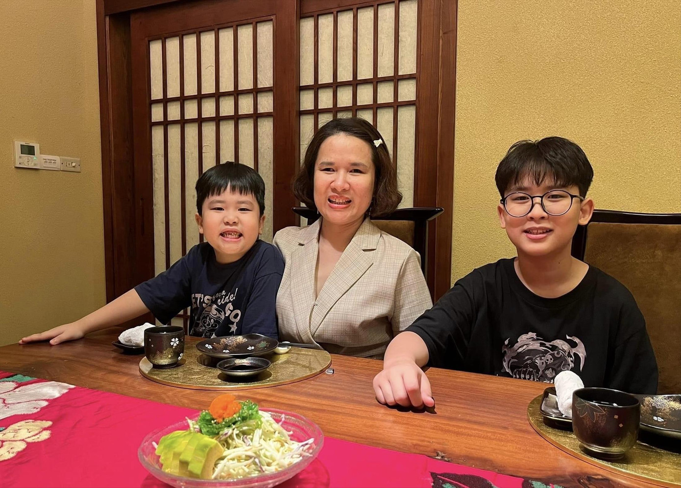 Chị Đỗ Thuý Hà, Chủ tịch Hội người mù quận Đống Đa, chụp ảnh cùng hai con trai Bill (bên phải) và Bell (bên trái)