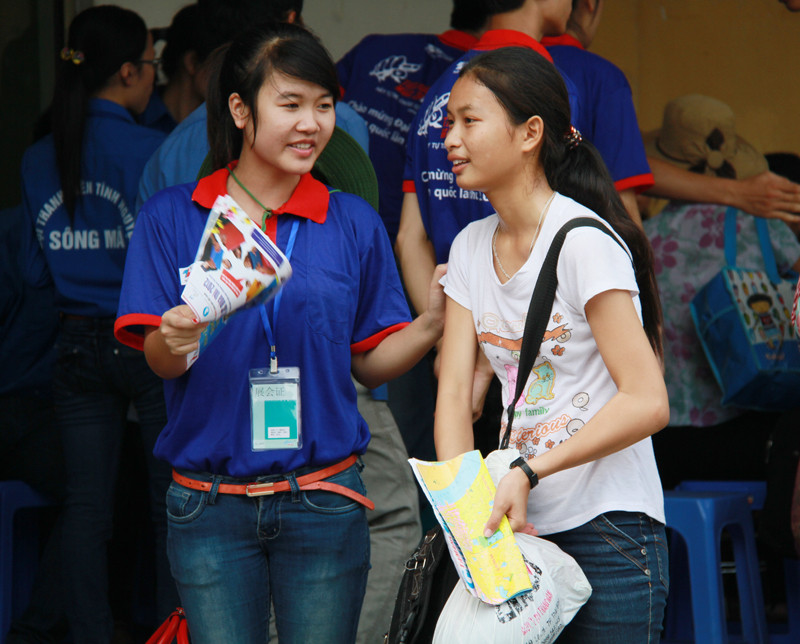 Trời nóng bức, nhưng thay vì quạt cho mình, nữ sinh viên tình nguyện phe phẩy tờ bản đồ, quạt mát cho một thí sinh. Ảnh: Trường Phong