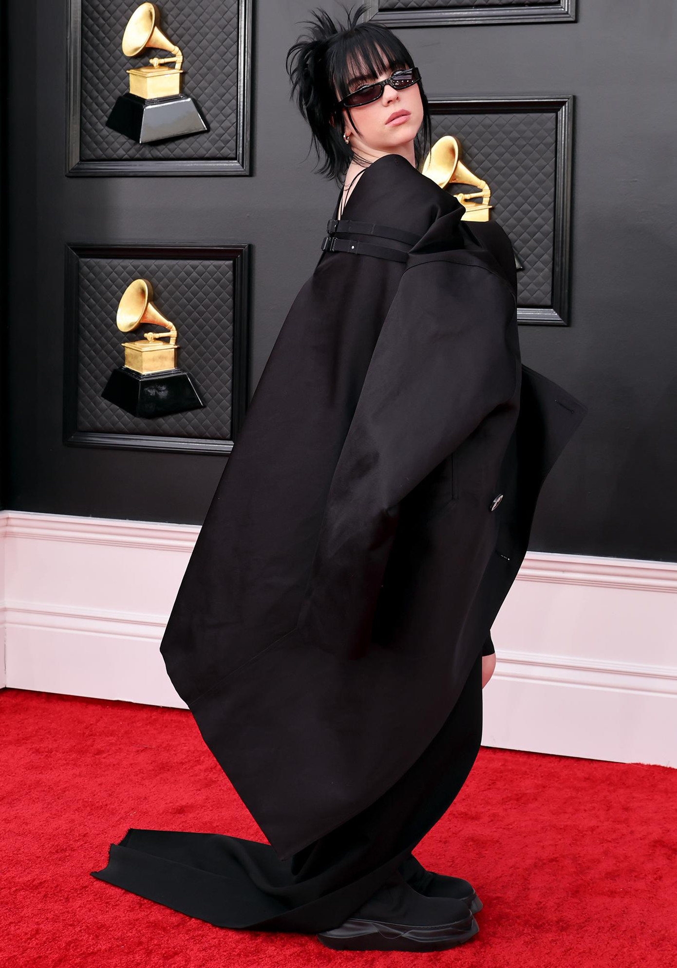 Billie Eilish chọn một chiếc váy rộng rãi với giày bốt và kính râm nhỏ.