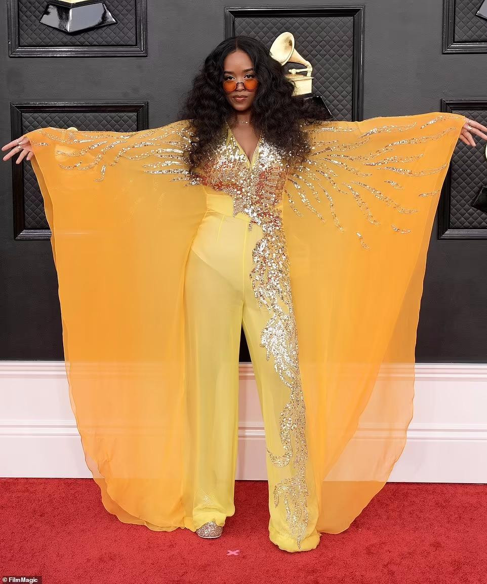 H.E.R mắc lỗi thời trang trong bộ áo liền quần màu vàng và cam được bao phủ bởi sequins vàng. Nữ ca sĩ 24 tuổi trông vừa già vừa &quot;sến&quot;.