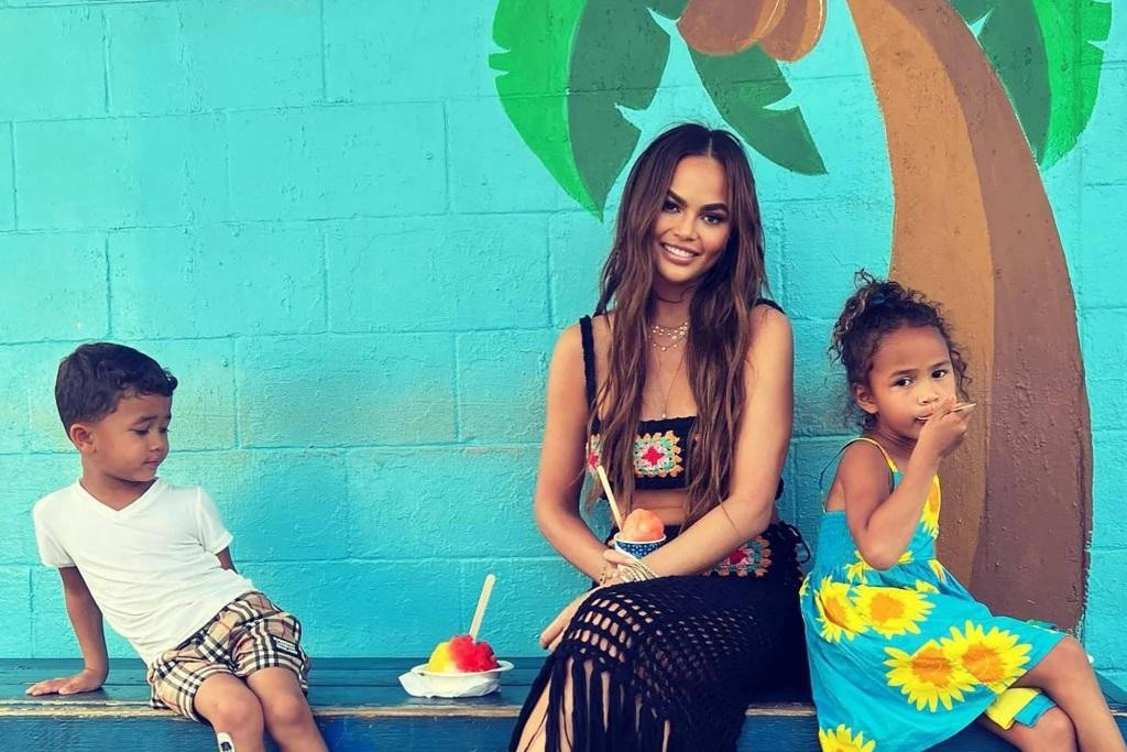 Chrissy Teigen (giữa) mặc trang phục đậm chất mùa hè, cùng hai con Miles (3 tuổi) và Luna (5 tuổi) thưởng thức món đá bào mát lạnh.