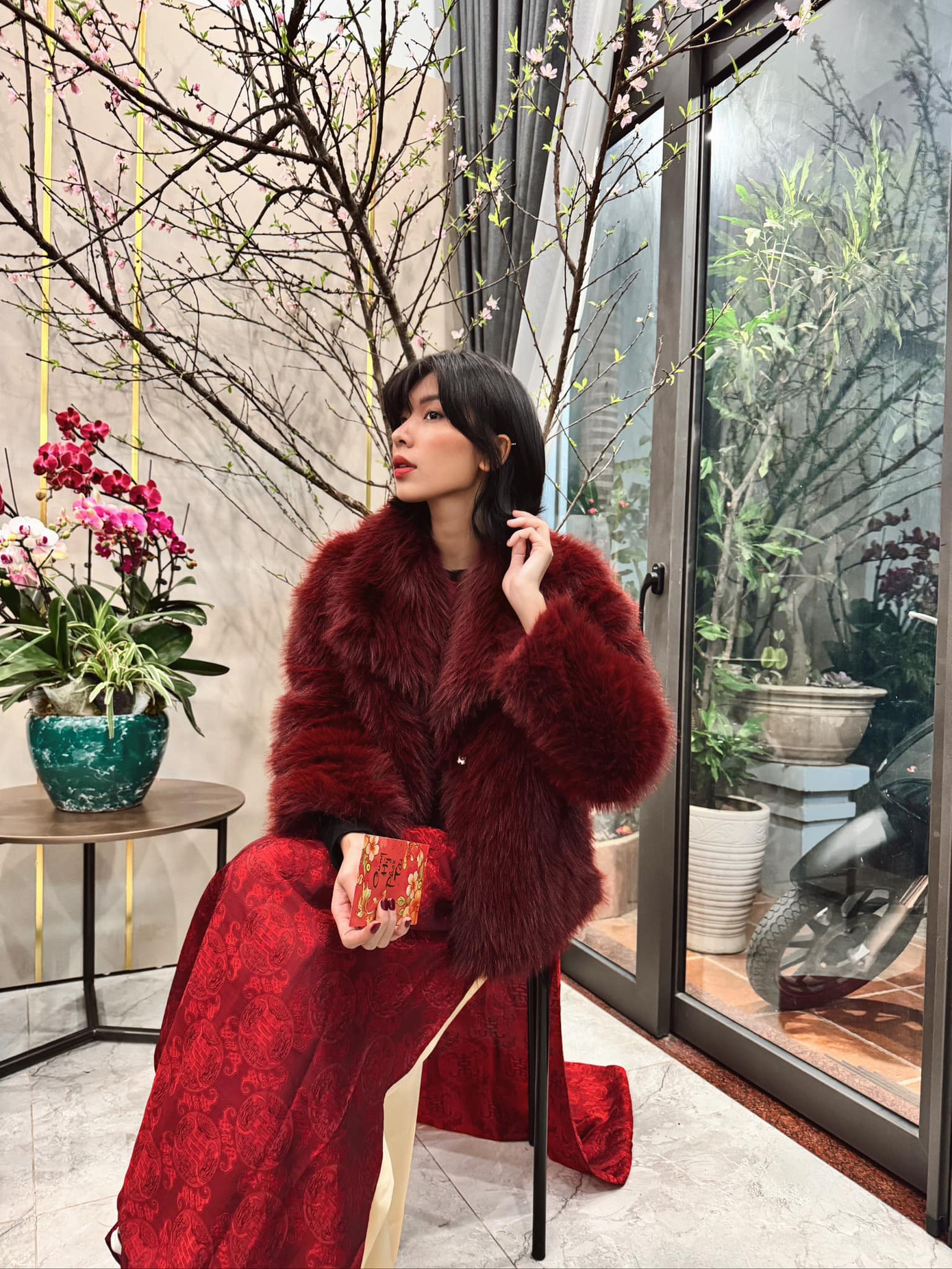 &quot;Bé Liên&quot; Đồng Ánh Quỳnh mặc áo dài lụa đỏ, phá cách với áo khoác lông tông màu cherry, trang điểm sắc sảo. &quot;Về nhà vẫn là em bé, vẫn được lì xì nhen.&quot; - nữ người mẫu viết.