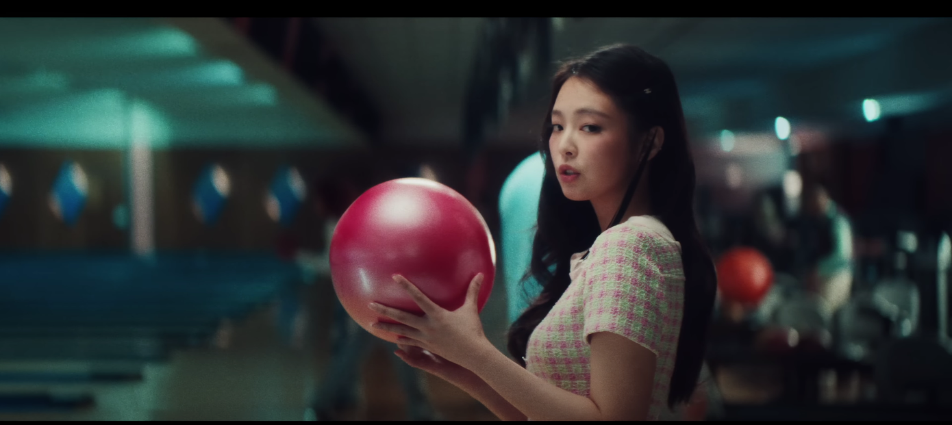 Lấy bối cảnh ở khu chơi bowling, Jennie BLACKPINK và Charles Melton đẹp đôi trong trang phục phối màu hồng - xanh, cùng diện với quần âu đen.