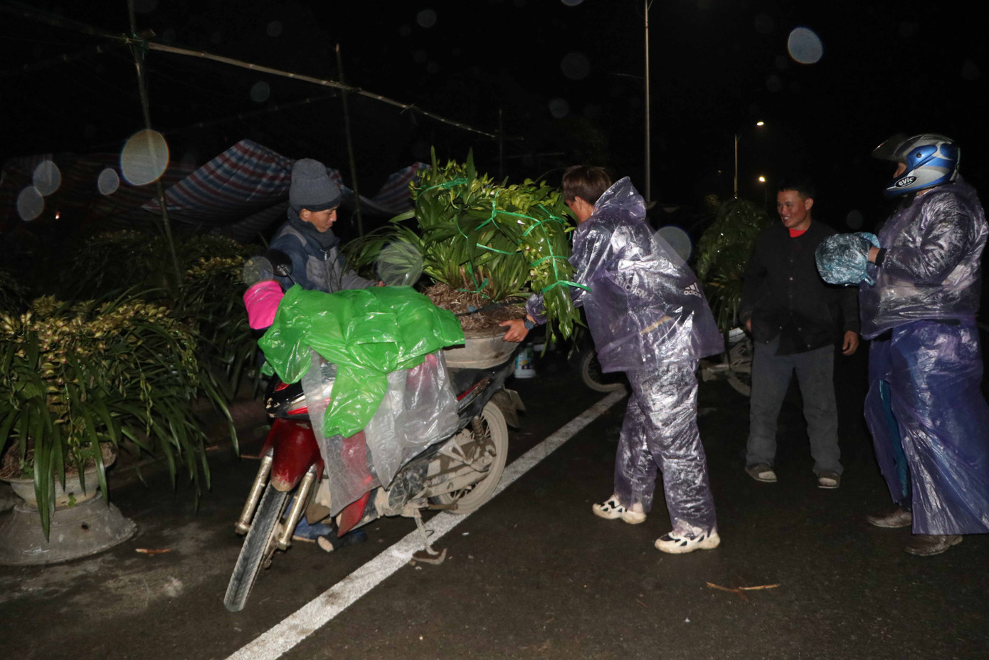Trời rét căm căm, không chỉ mặc ấm, người dân còn trang bị thêm quần, áo mưa tránh mưa.