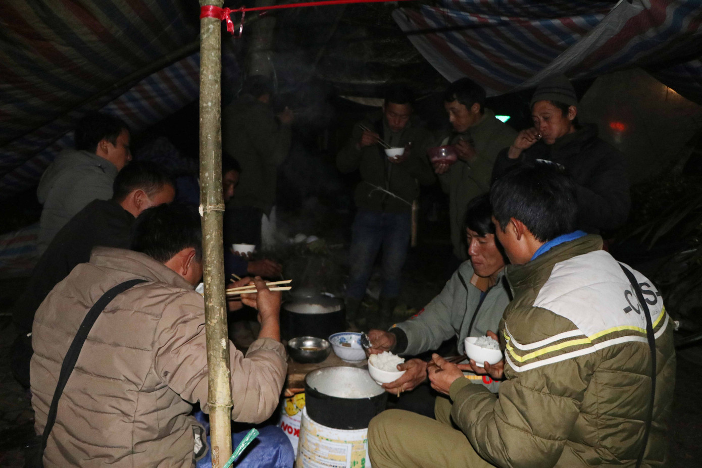 Sau những chuyến chở địa lan xuống phố, bà con người Mông (Lai Châu) tranh thủ ăn vội miếng cơm trong túp lều tạm sơ sài được dựng bằng vài thân tre và tấm bạt phủ lên.