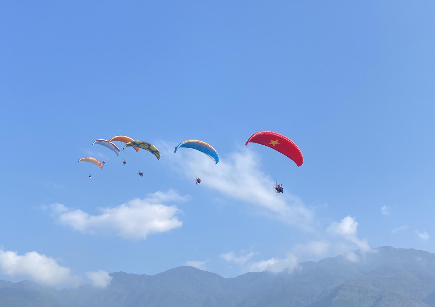 Các vận động viên trình diễn bay dù lượn và du khách trải nghiệm bay cùng phi công trên bầu trời.