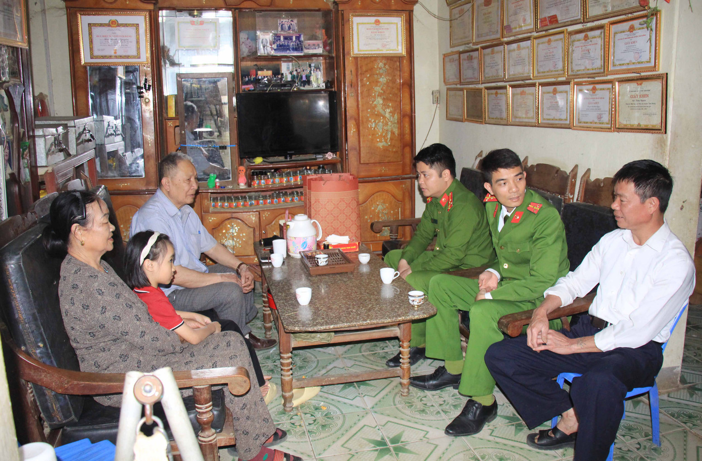 Thượng úy Nguyễn Văn Tùng (thứ hai bên phải) cùng cán bộ Phòng Cảnh sát kinh tế thăm hỏi, chia sẻ khó khăn với gia đình "Em nuôi của Đoàn".