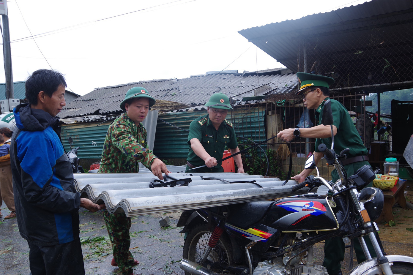 Cán bộ, chiến sĩ Bộ Chỉ huy Bộ đội Biên phòng tỉnh Lai Châu vận chuyển tấm lợp giúp dân lợp lại mái nhà. Cán bộ, chiến sĩ Bộ Chỉ huy Bộ đội Biên phòng tỉnh Lai Châu vận chuyển tấm lợp giúp dân lợp lại mái nhà.