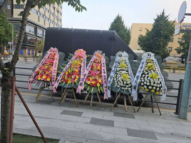 Hình ảnh vòng hoa được đặt trước trụ sở HYBE, tuy nhiên đã bị chuyển đi ngay sau đó.