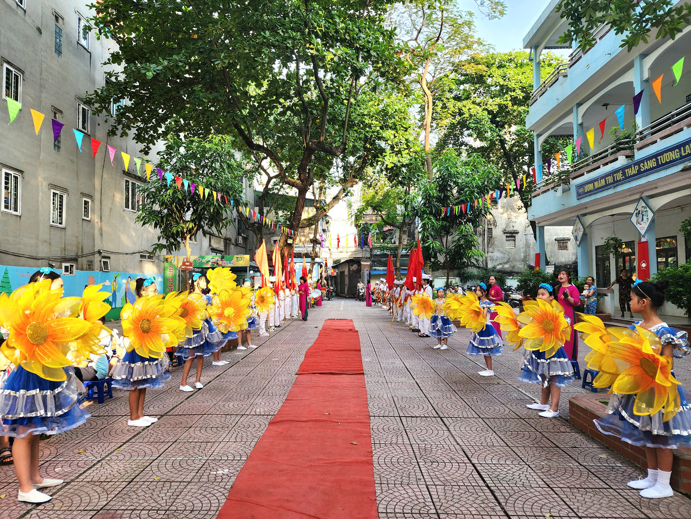 Các bạn học sinh giương cao những bông hoa rực rỡ, đợi đón chào các em học sinh lớp 1 và Đại biểu các cấp về dự lễ khai giảng.