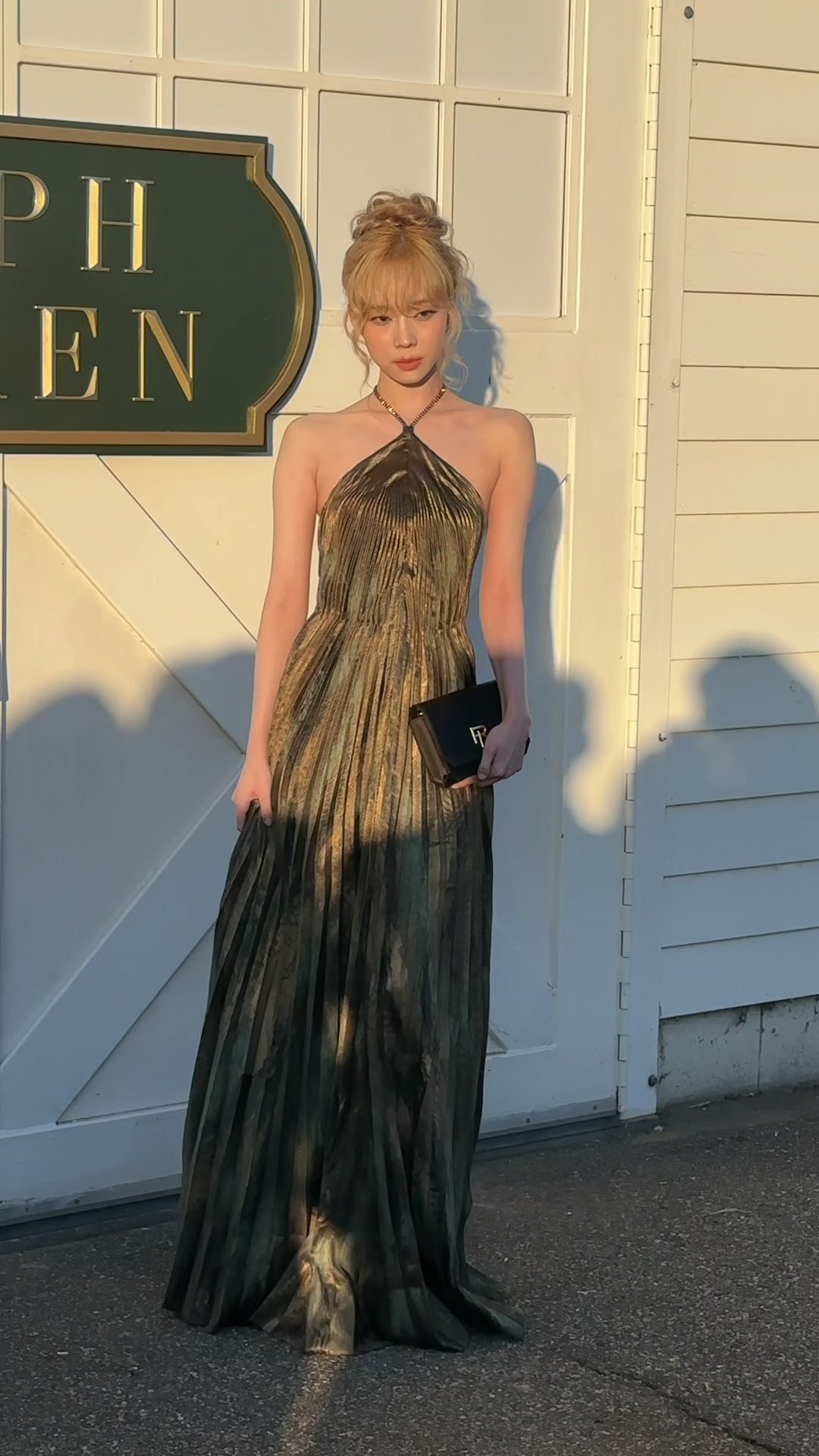 Winter lựa chọn váy satin xếp ly kết hợp với túi cầm tay nhỏ gọn.