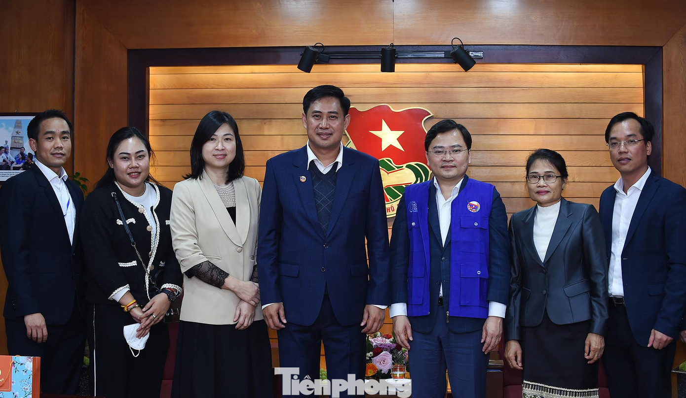 Các đại biểu chụp ảnh lưu niệm. Anh A Lun Xay Sủn Nạ Lạt tặng anh Nguyễn Anh Tuấn chiếc áo xanh của thanh niên tình nguyện Lào tham gia phòng chống dịch COVID-19. Ảnh: Xuân Tùng.